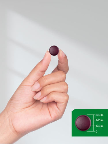Hand holding a small purple object with a size reference on a green overlay.