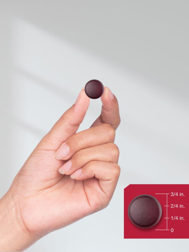 Hand holding a maroon circular object with a size measurement inset.