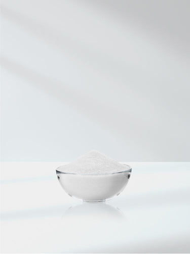 Small glass bowl filled with white powder on a white background
