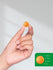 Hand holding an orange object with a size reference on a gray background