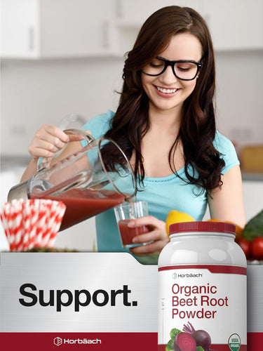 View 6 Young woman smiling while pouring a red drink into a glass, with a jar of Organic Beet Root Powder next to her.
