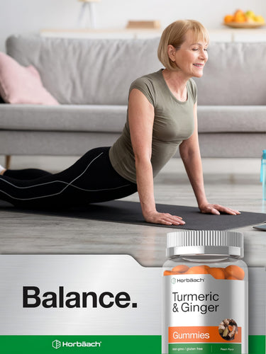 View 6 Older woman doing an upward-facing yoga pose on a mat, smiling, with a bottle of Turmeric & Ginger Gummies nearby.