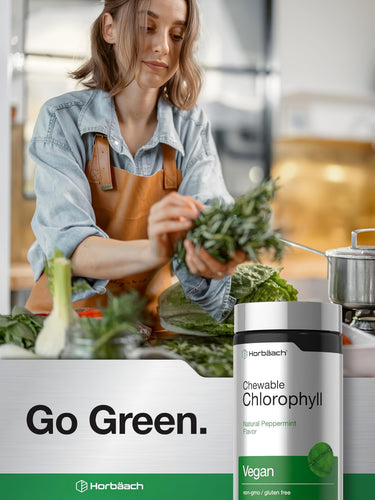 View 6 A young woman prepares fresh greens with a Horbäach Chewable Chlorophyll bottle in the foreground.