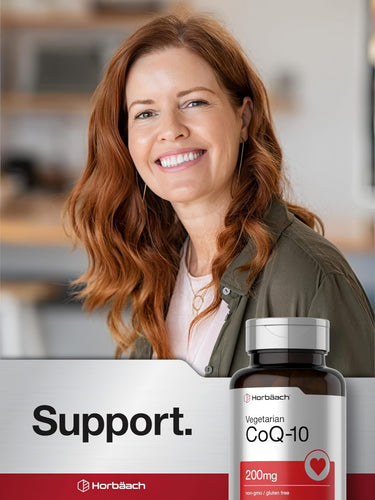 View 6 Middle-aged woman with red hair smiling at the camera next to a Horbaach CoQ10 bottle.