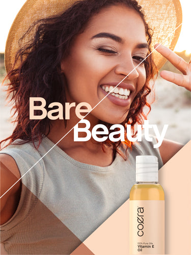 View 13 Lifestyle image of smiling adult wearing a sun hat with Coera Vitamin E Oil bottle and graphic stating Bare Beauty.