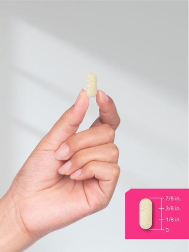 Hand holding a pill with a measurement chart on a gray background