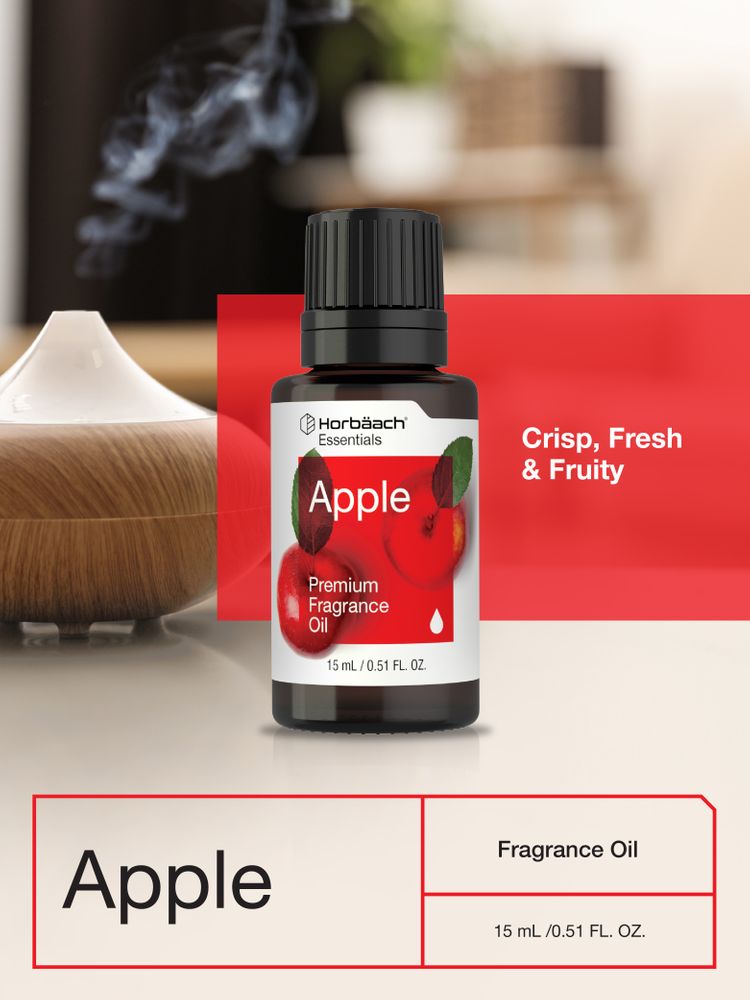 Glass bottle of apple essential oil near fresh apples on a wooden table.  Essential oil is used to fill lamps, perfumes and in cosmetics. Stock Photo